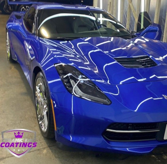 Blue Corvette sports car with a shiny, reflective coating inside a detailing shop.