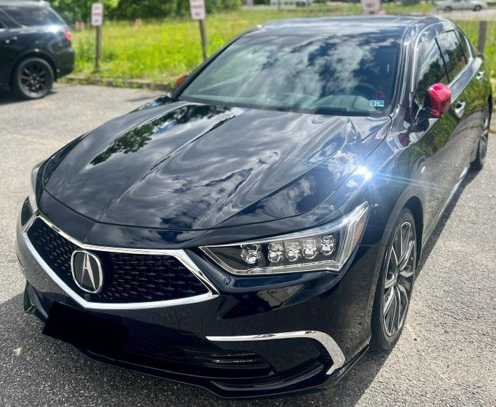 Black Acura sedan with red side mirrors parked outside.