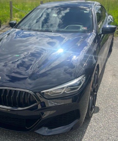 Black BMW coupe parked outdoors, glossy paint reflecting sunlight.
