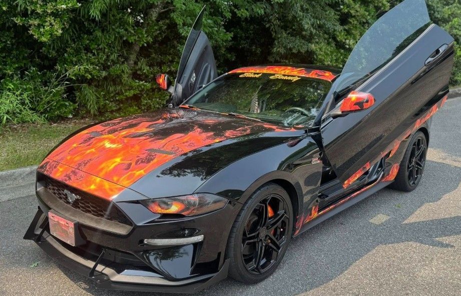 Black Mustang with orange flame design and gullwing doors open.