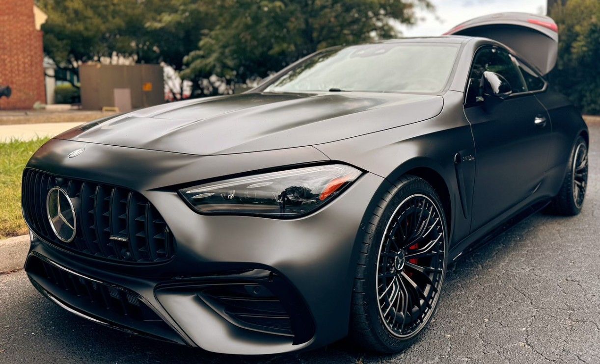Matte black Mercedes-AMG coupe with the trunk open parked on a street.