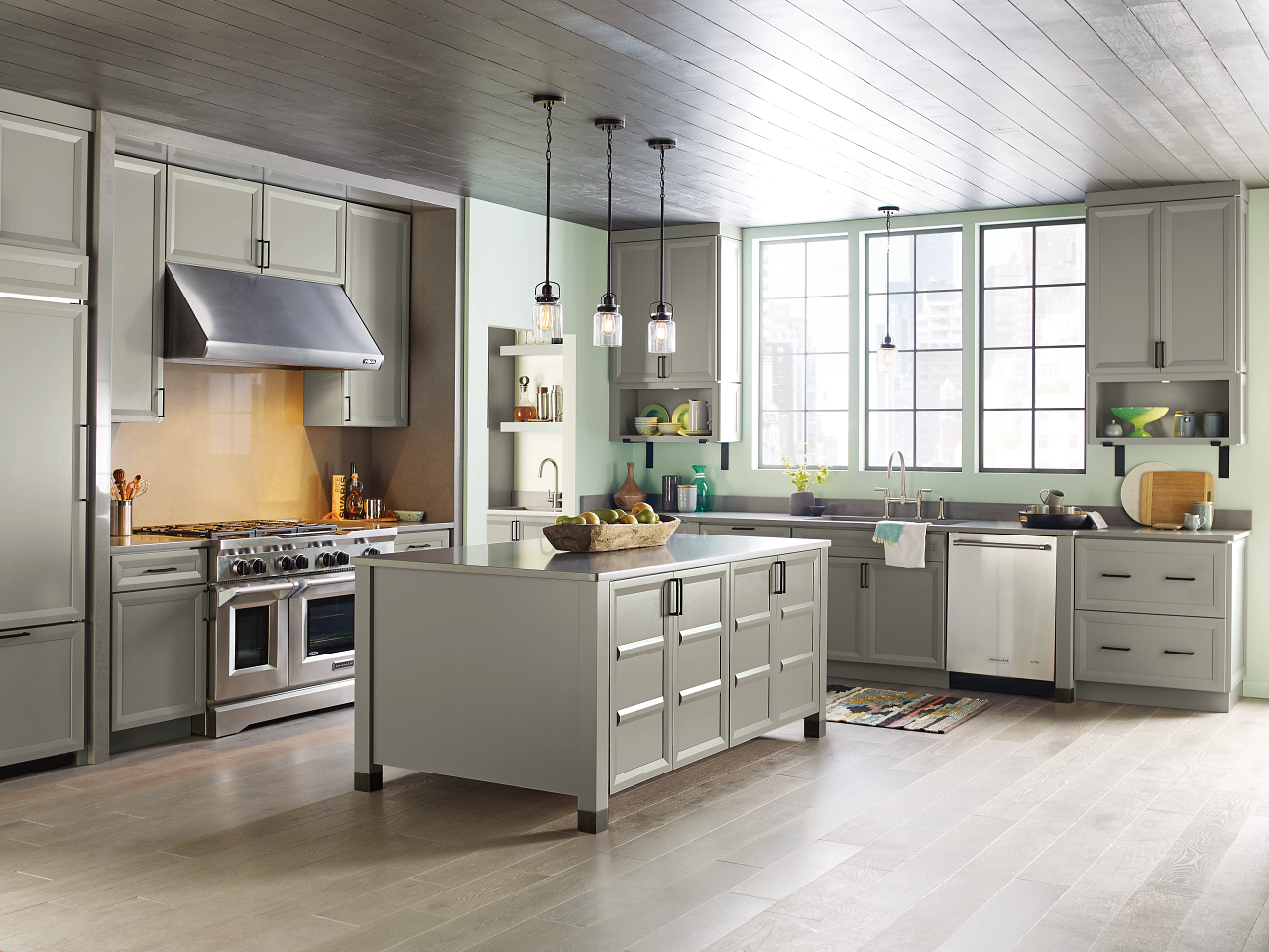 A kitchen with a large island in the middle and stainless steel appliances.