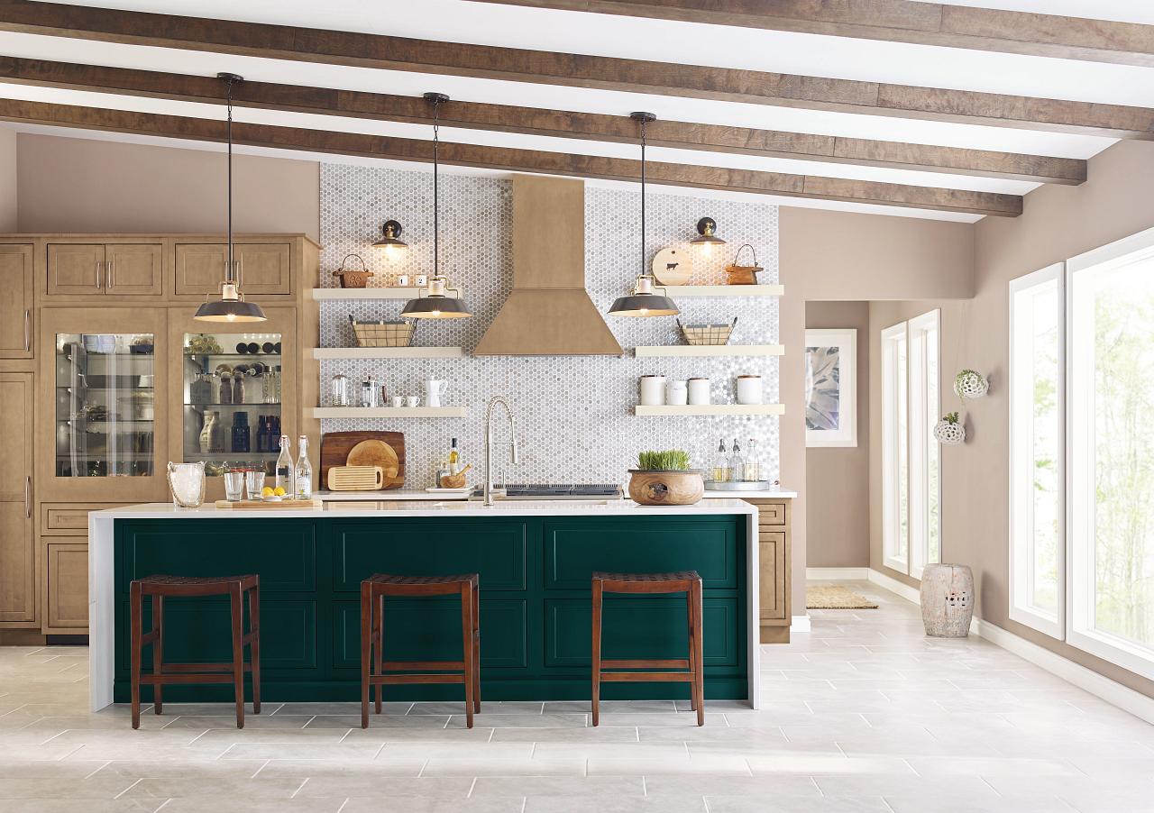 A kitchen with green cabinets , wooden cabinets , stools and a large island.