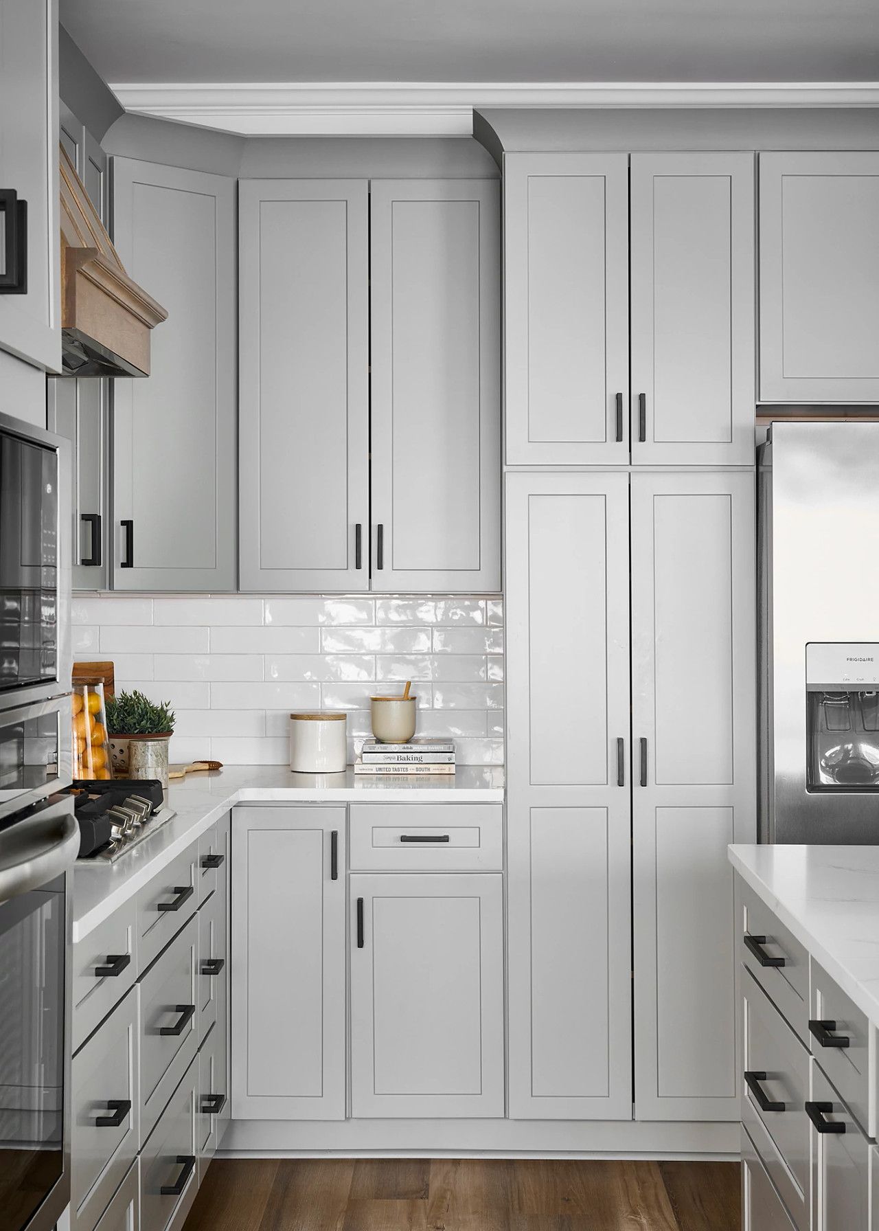 A kitchen with white cabinets , stainless steel appliances , a sink , and a refrigerator.