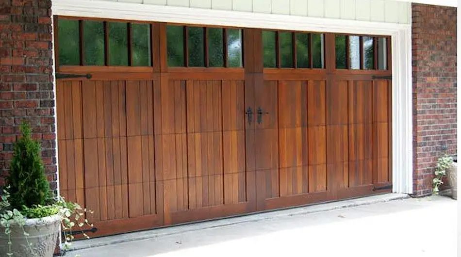 Wooden garage door with glass panels above, framed by brick and white trim.
