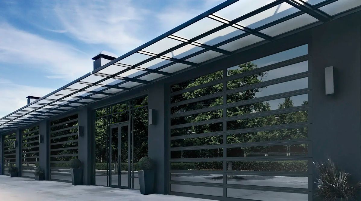 Four glass garage doors with red trim and yellow bollards, set in a modern building.