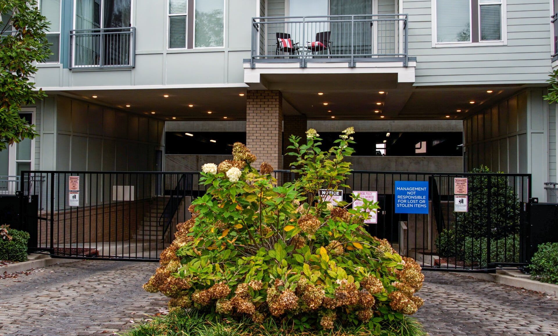 A building with a fence and a bush in front of it
