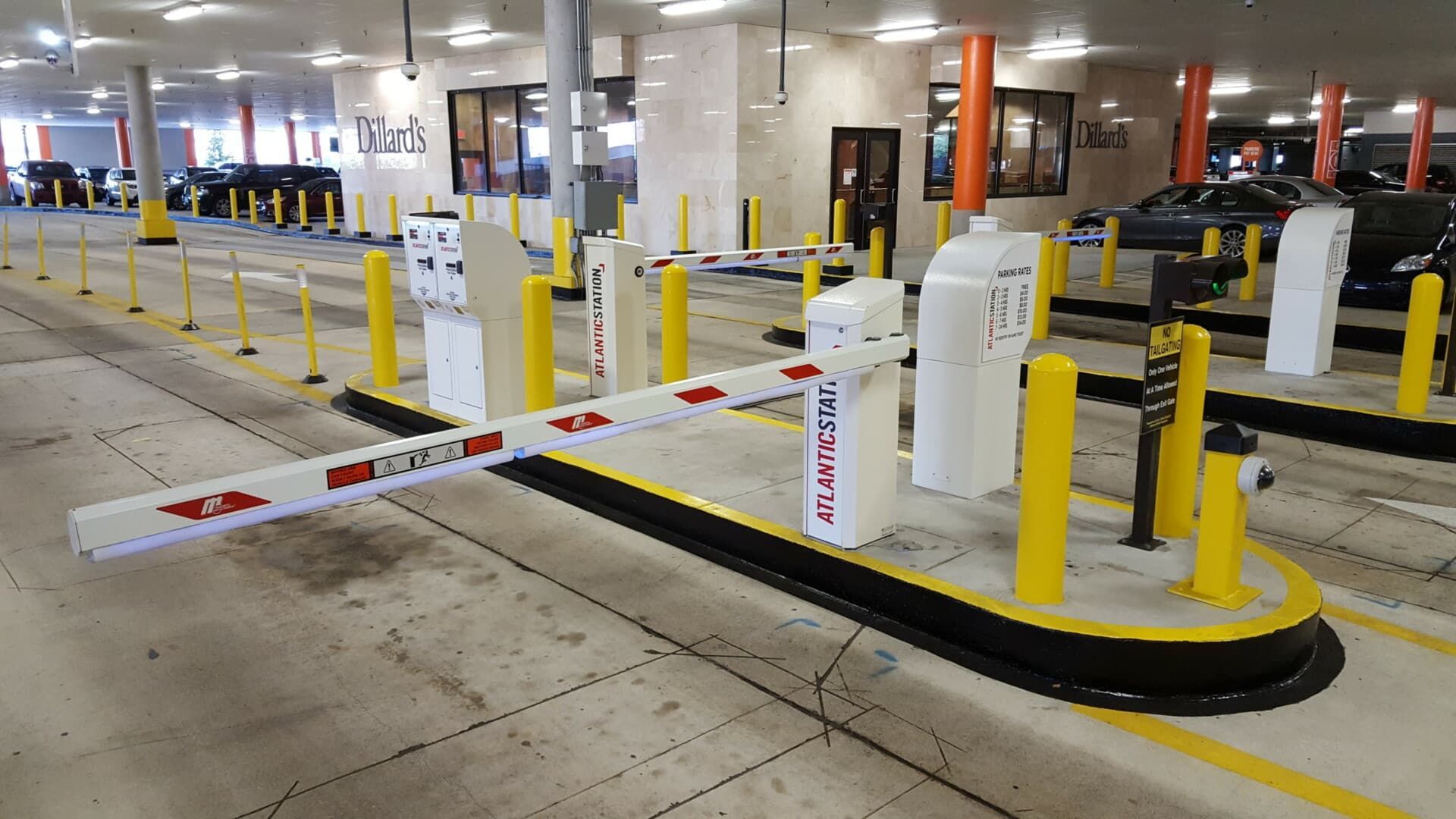 A parking garage with a barrier and yellow poles