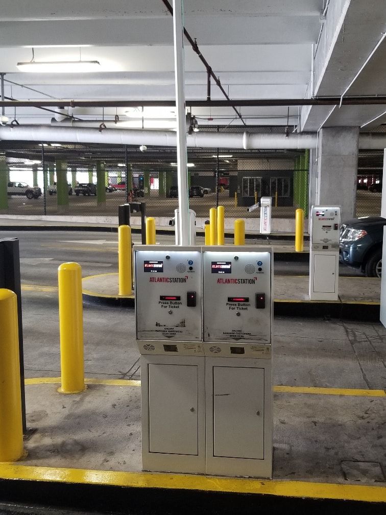 Two parking meters in a parking garage with yellow poles