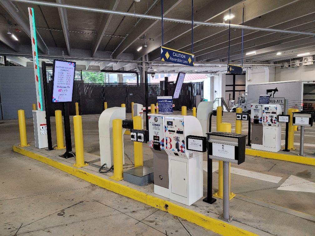 A parking garage with a lot of parking meters and a screen.