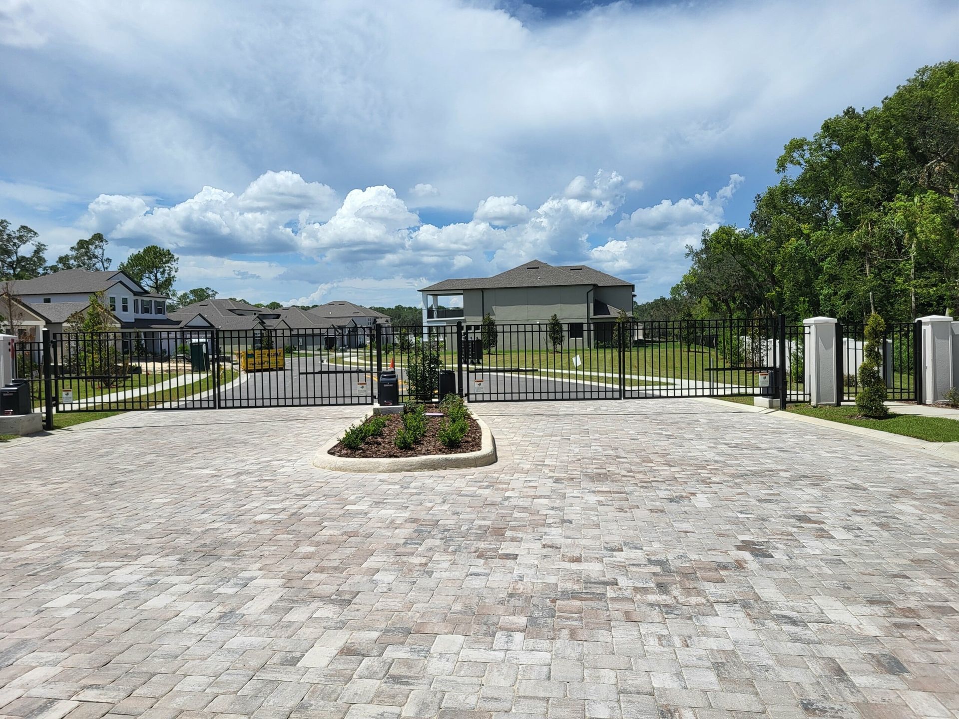 A brick driveway with a gate in the middle of it