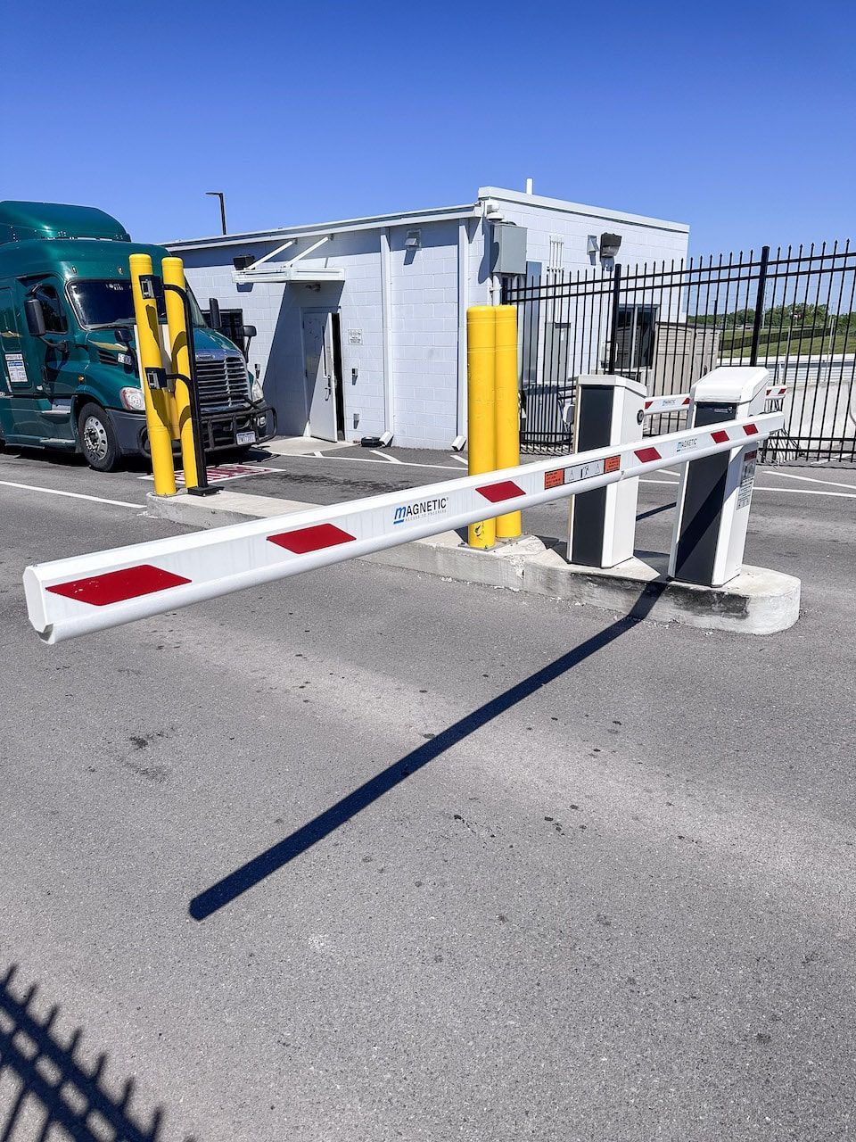 A green semi truck is parked behind a barrier