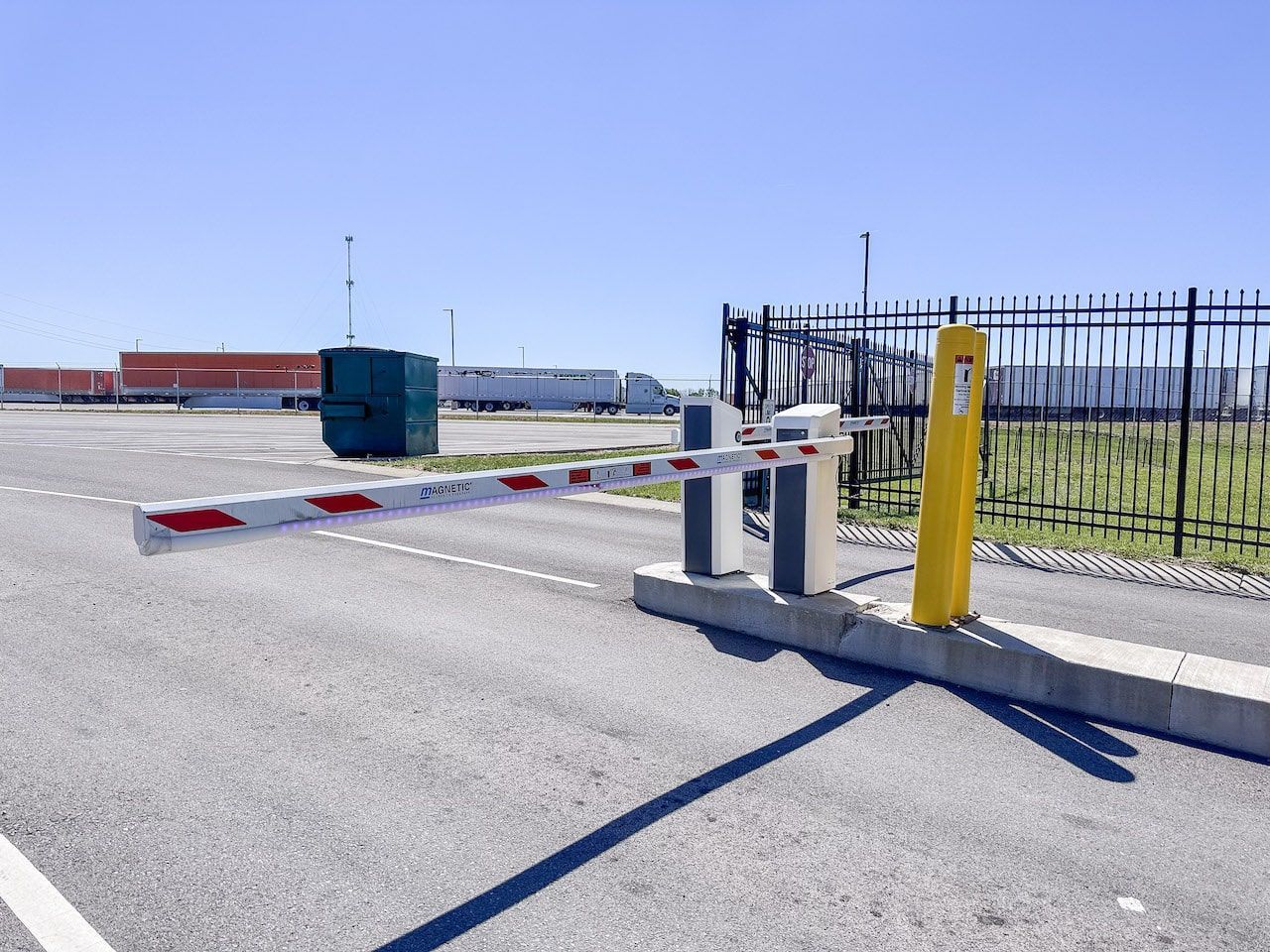 A parking lot with a barrier and a yellow pole.