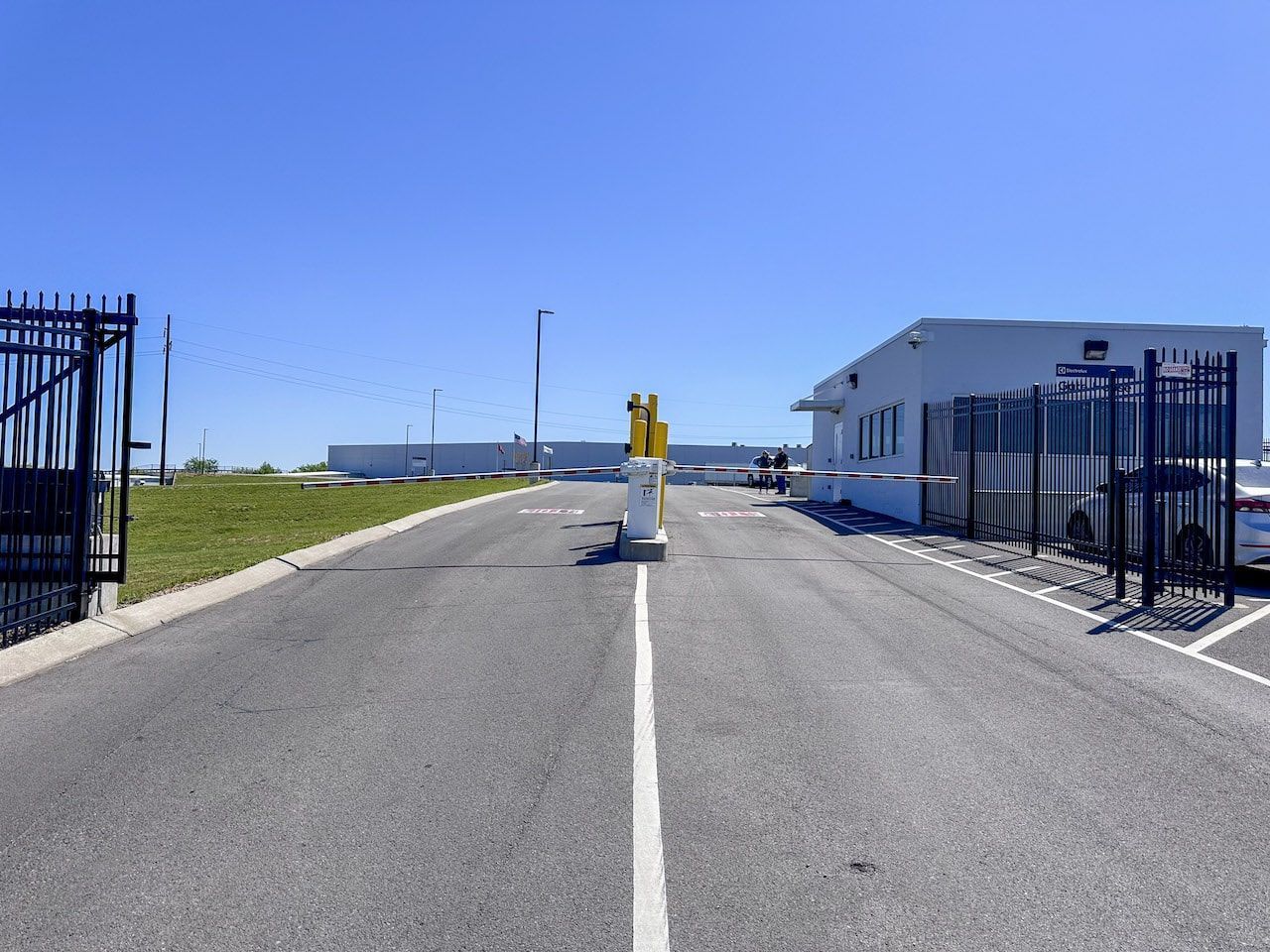 A road leading to a building with a fence and a gate.