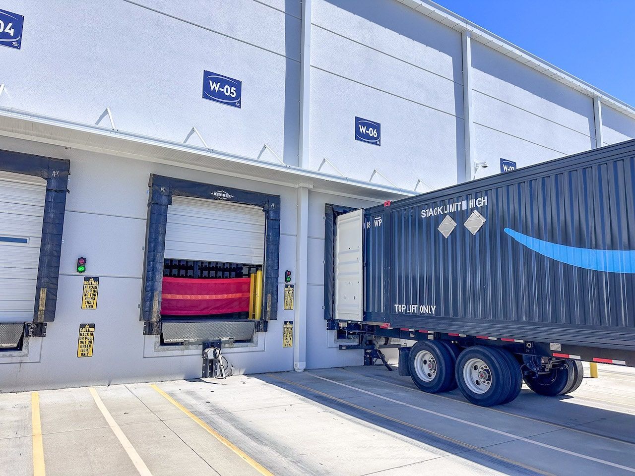 An amazon truck is docked at a warehouse.