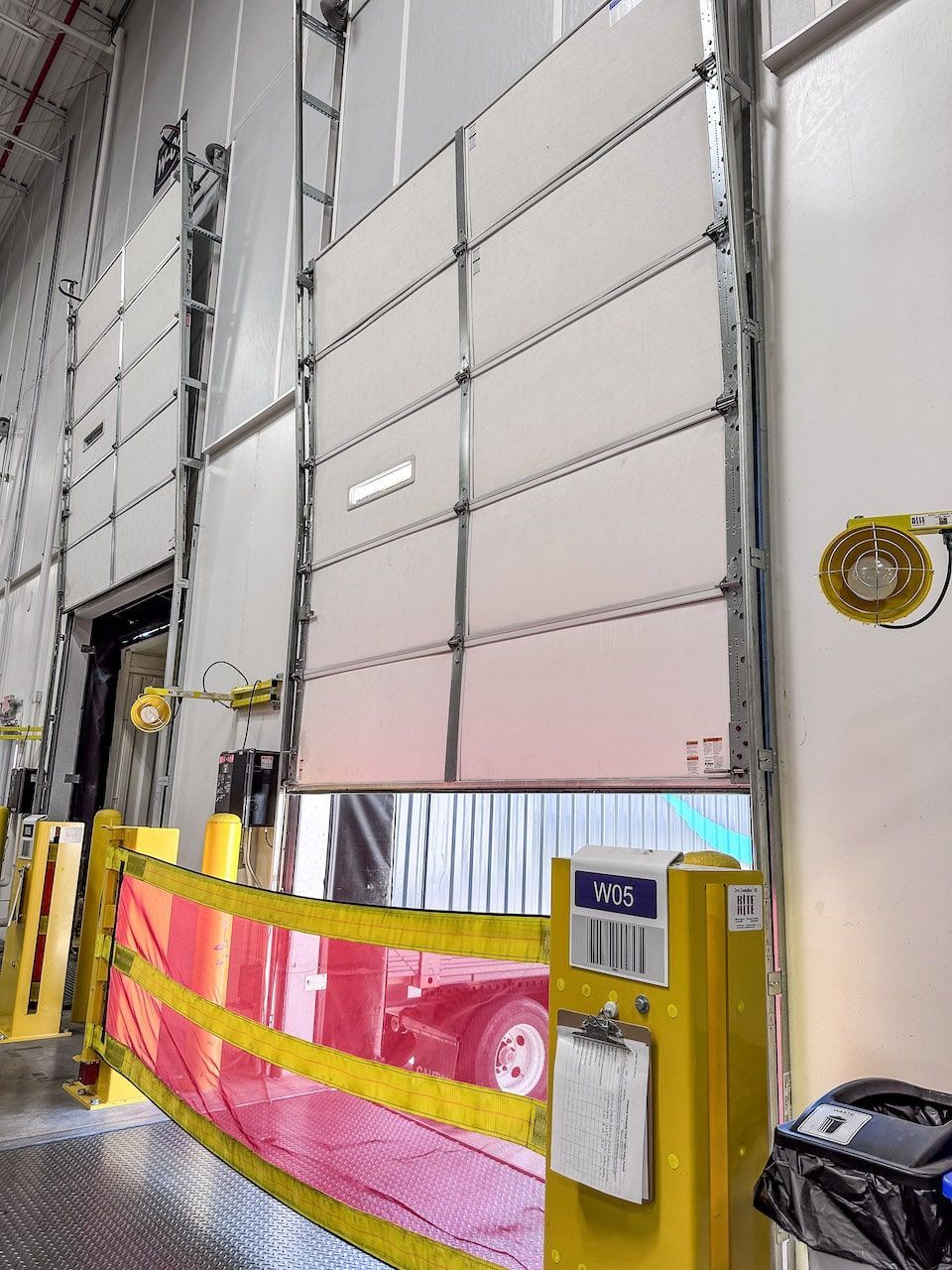 A warehouse with a red truck behind a yellow barrier.