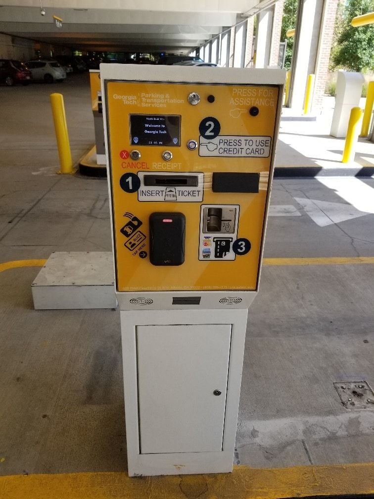 A yellow and white parking meter in a parking garage