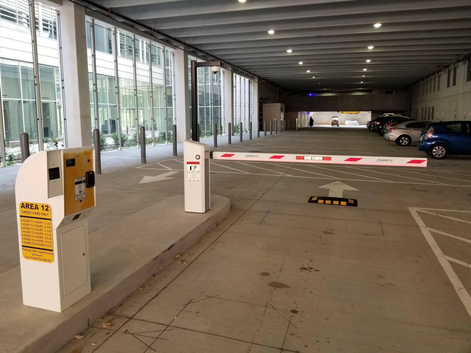 A parking garage with cars parked in it and a barrier.