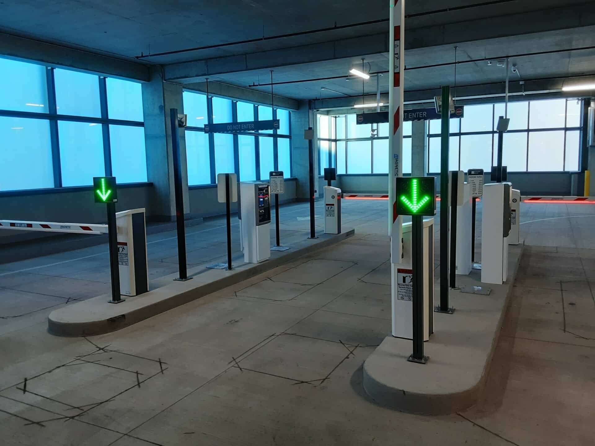 A parking garage with a lot of gates and arrows pointing down.
