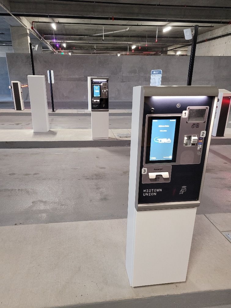A row of kiosks in a parking garage with a screen on them