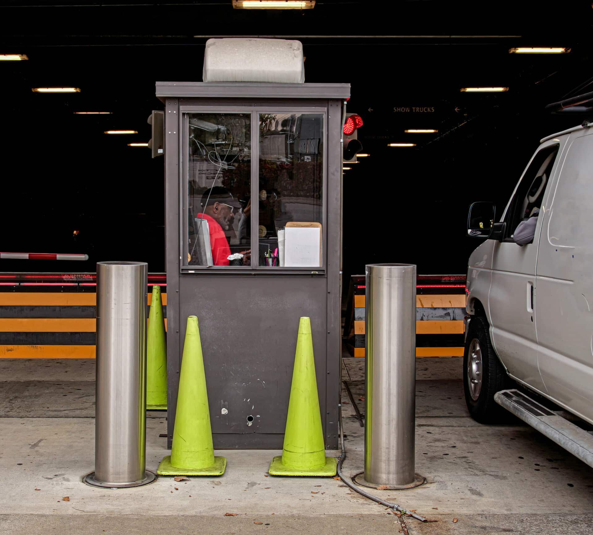 A gray van is parked in front of a security booth