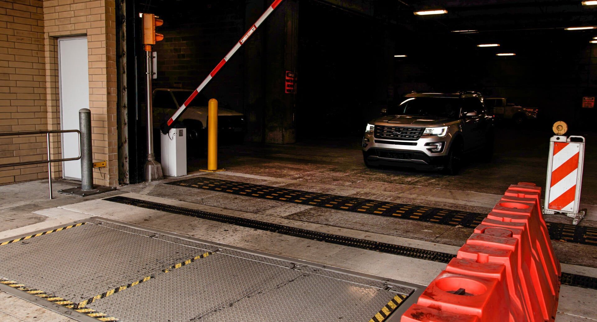 A car is driving through a gate in a parking garage.