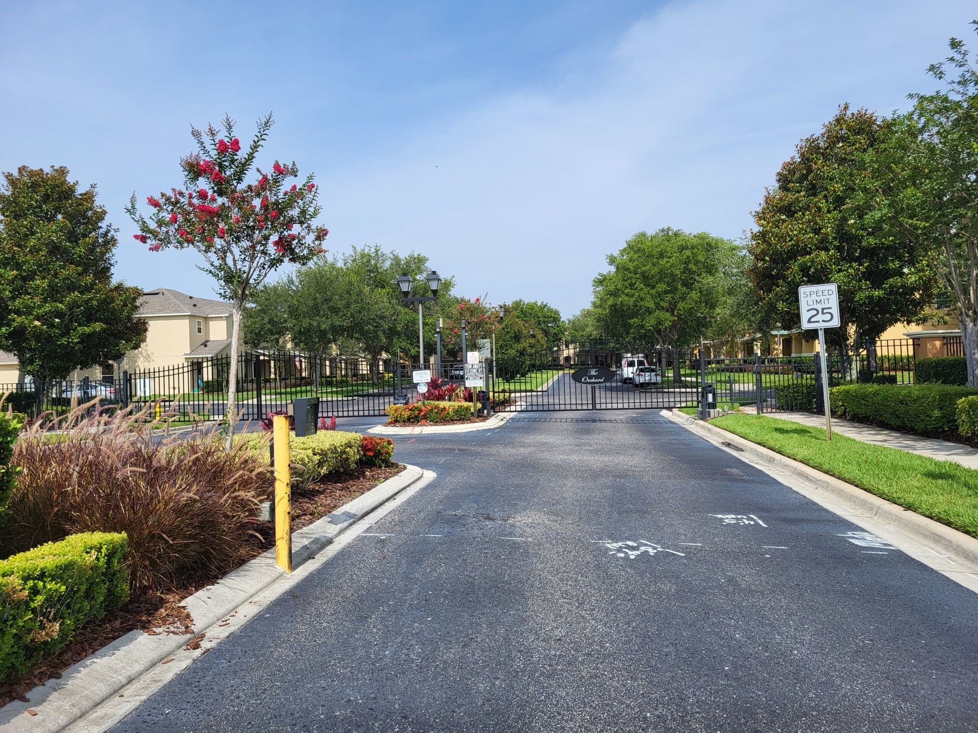 A gated entrance to a residential area with trees and bushes
