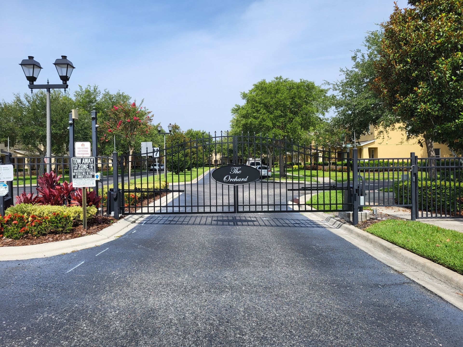 A gated entrance to a residential area with a black gate