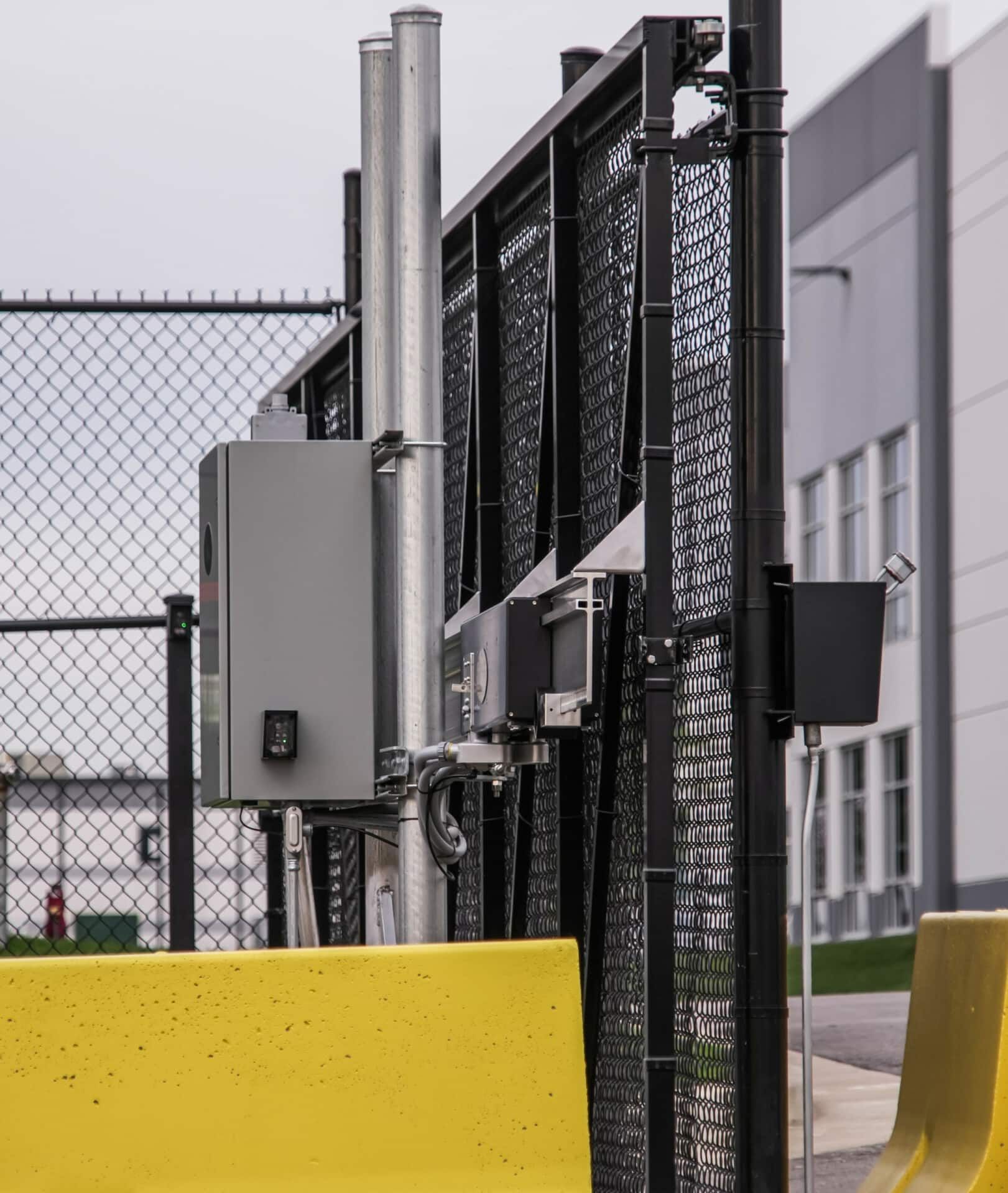 A yellow barrier is in front of a chain link fence