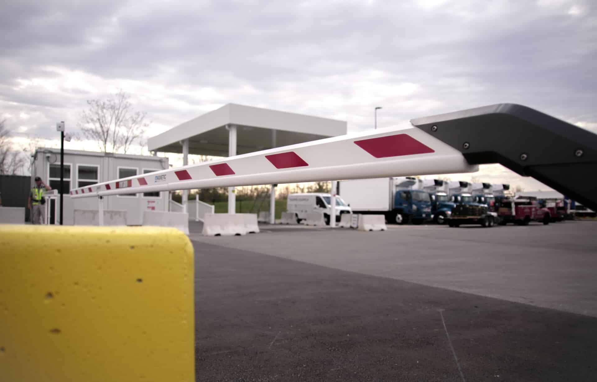 A yellow pole is in front of a barrier in a parking lot.