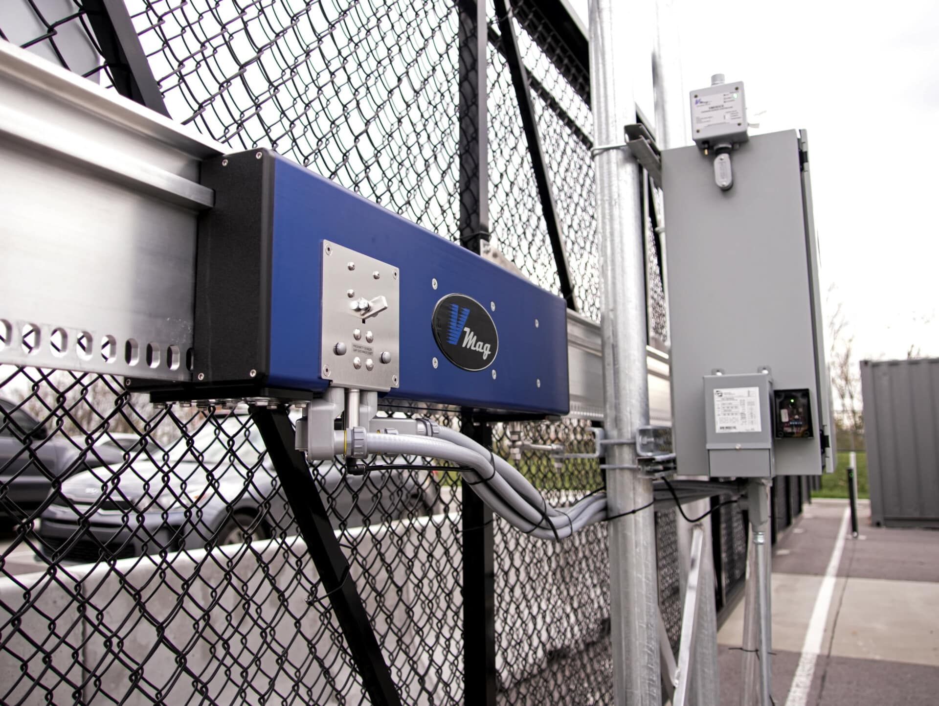A blue box is attached to a chain link fence