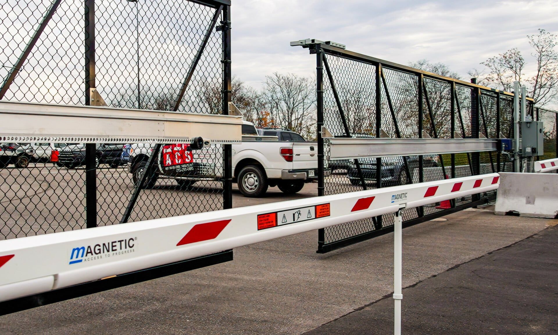 A white truck is parked in a parking lot behind a fence.