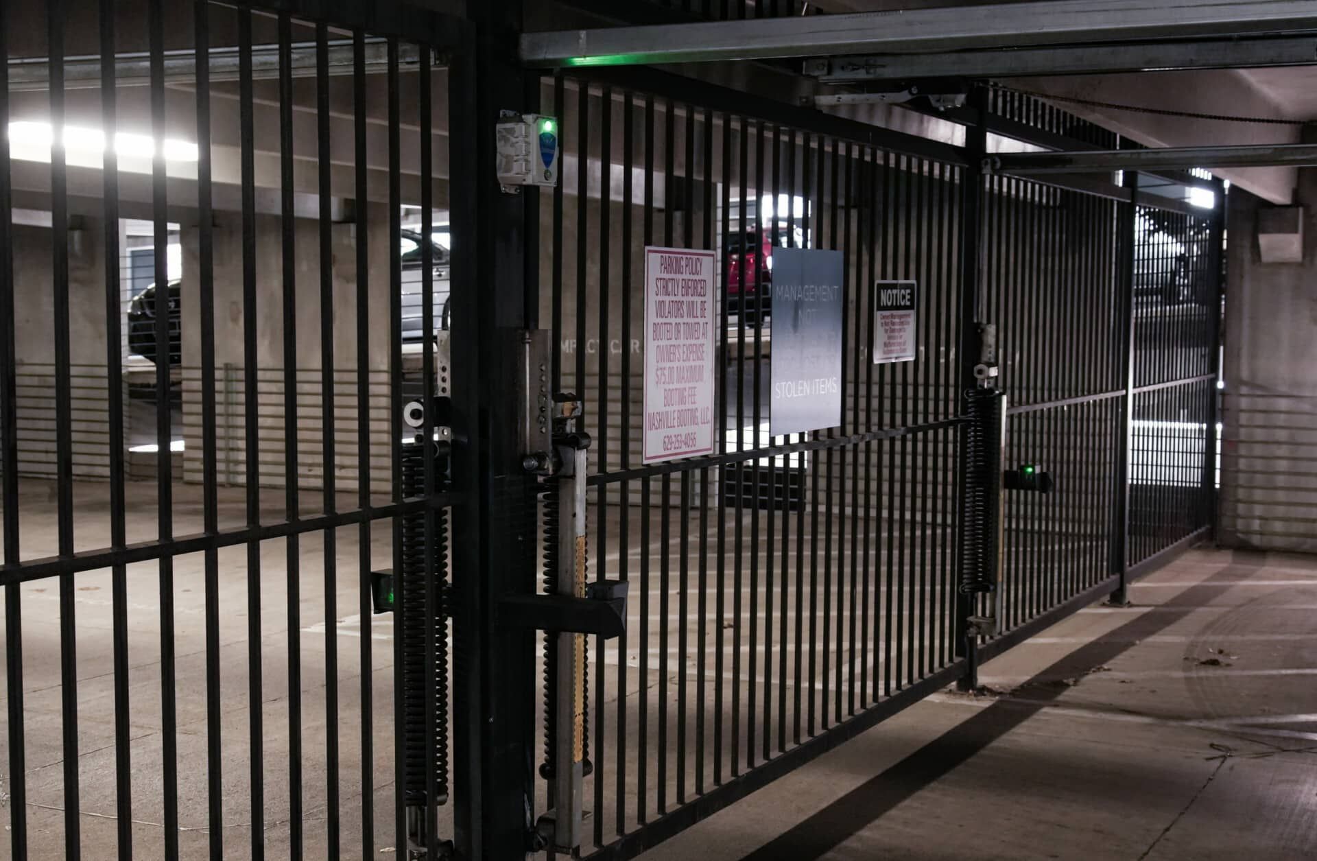 A fence in a parking garage with a sign that says no parking