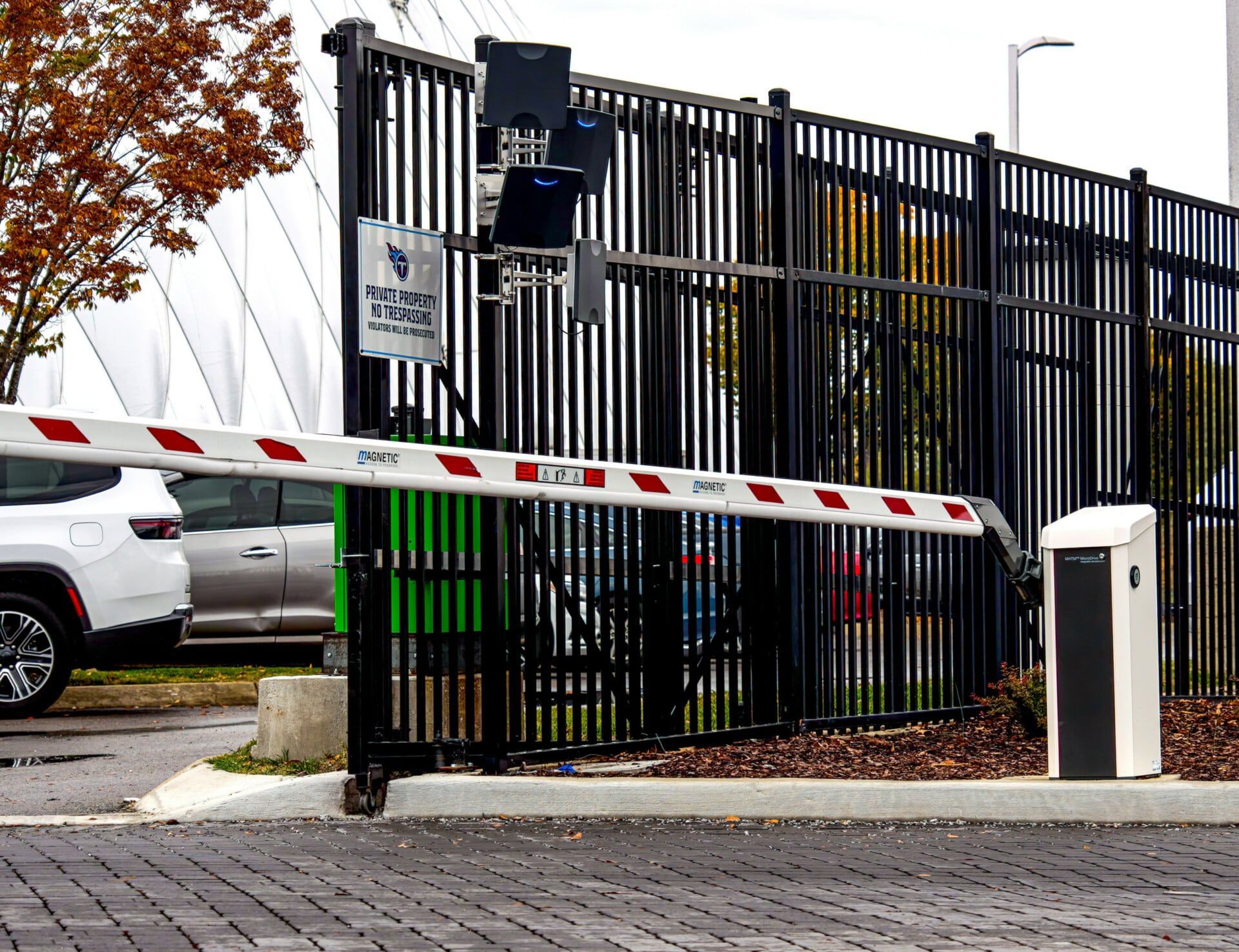 A car is parked in front of a gate with a barrier.