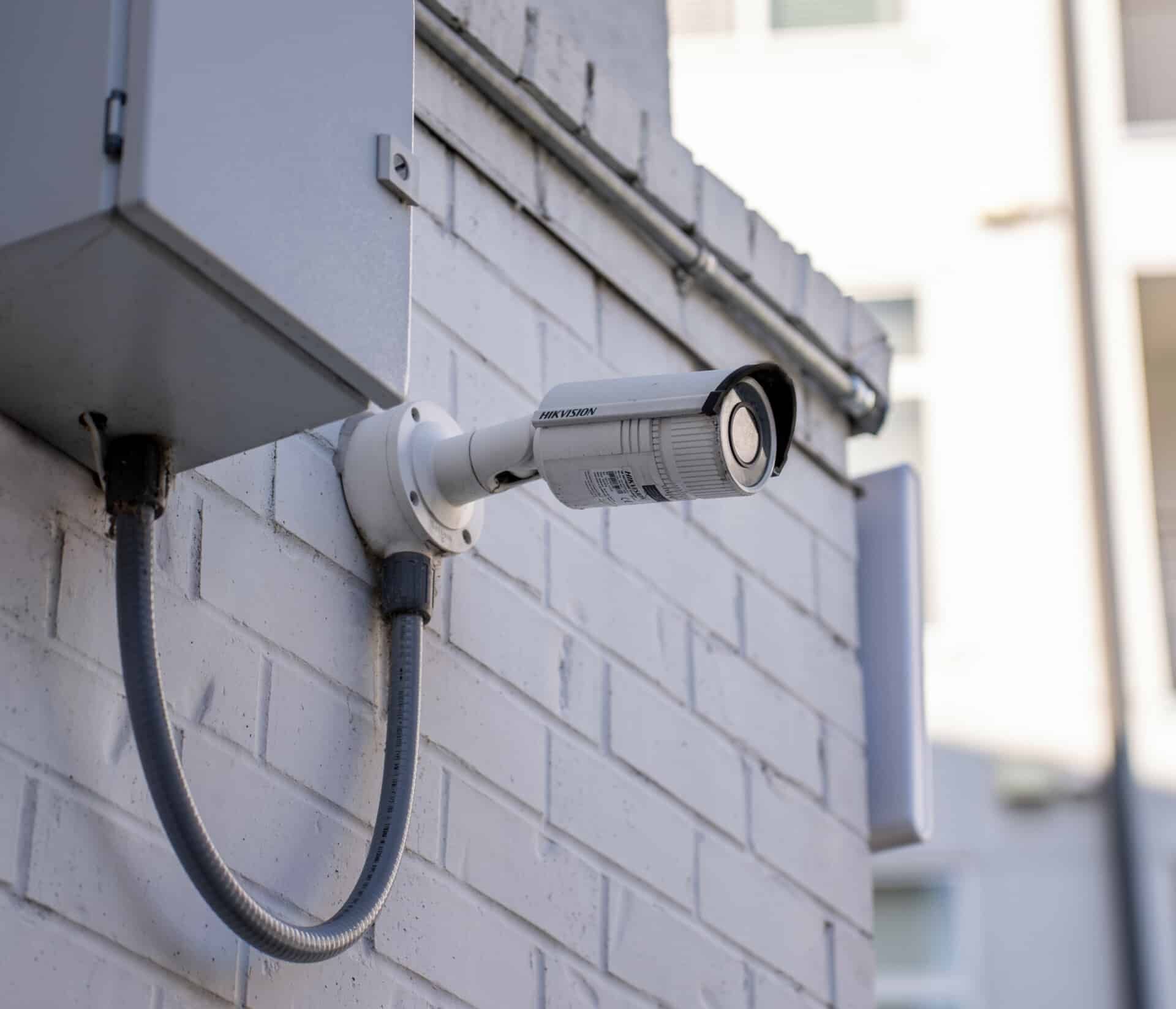 A security camera is mounted on the side of a brick building.