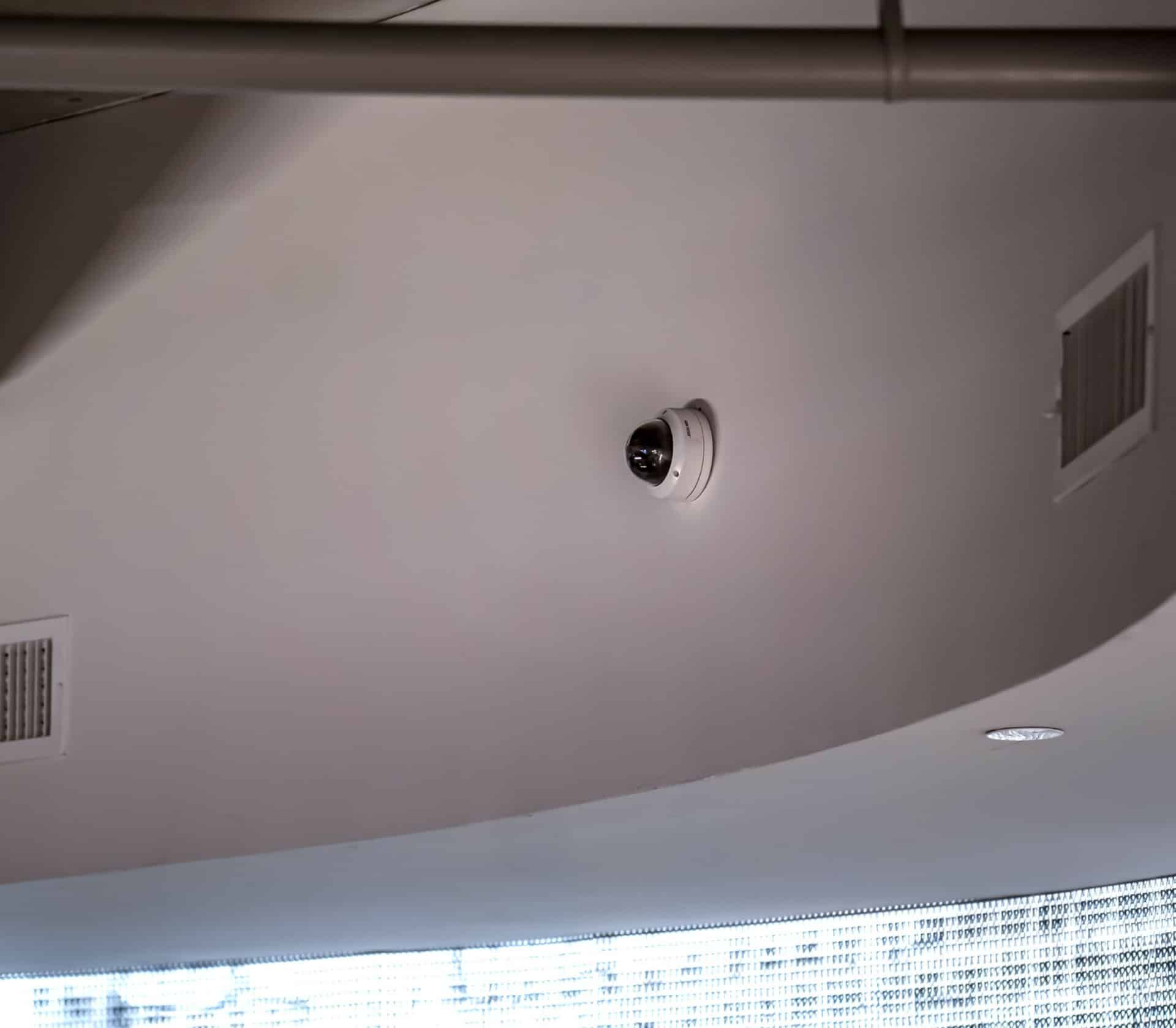 A security camera is hanging from the ceiling of a building.
