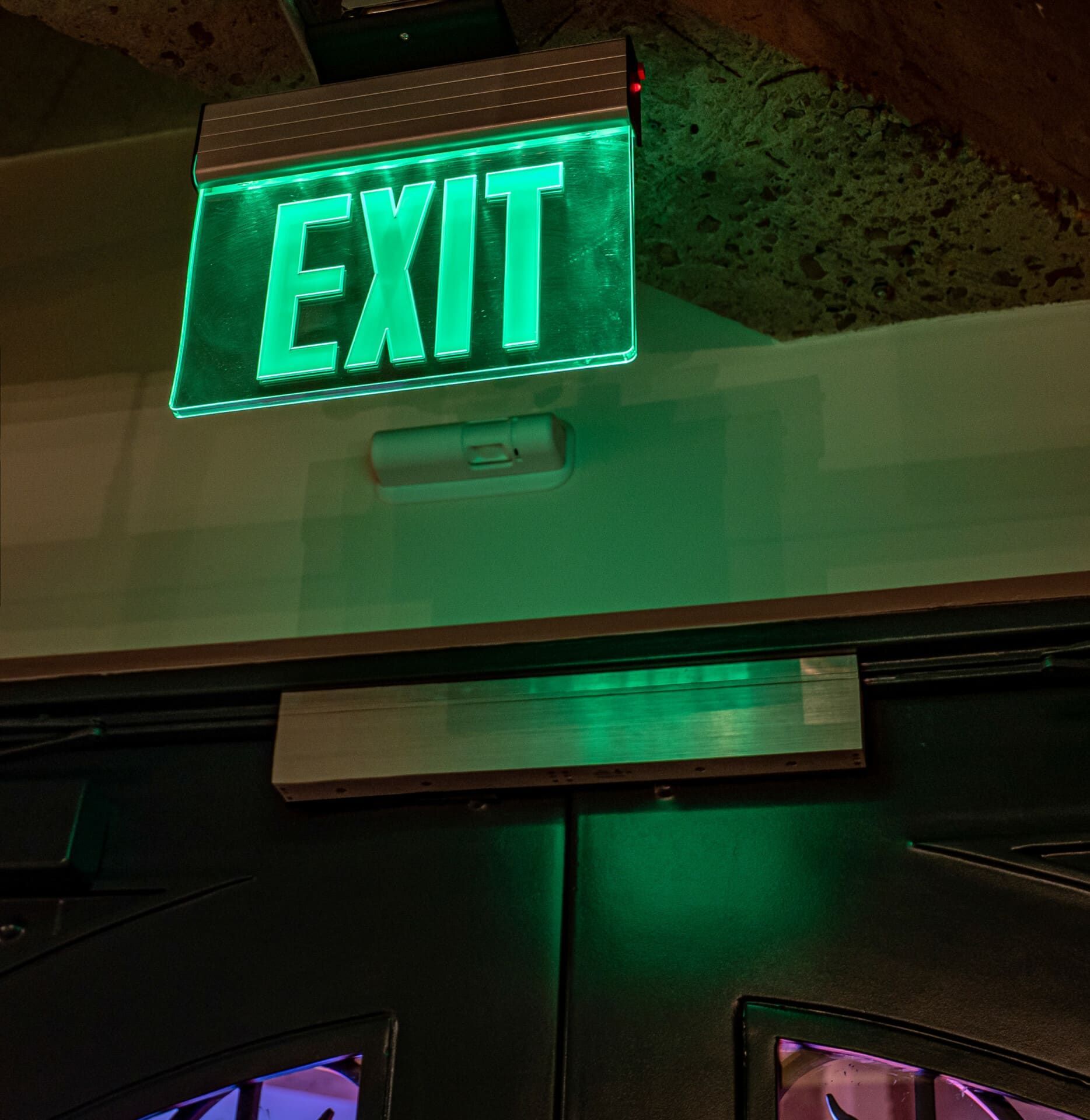 A green exit sign hangs above a door
