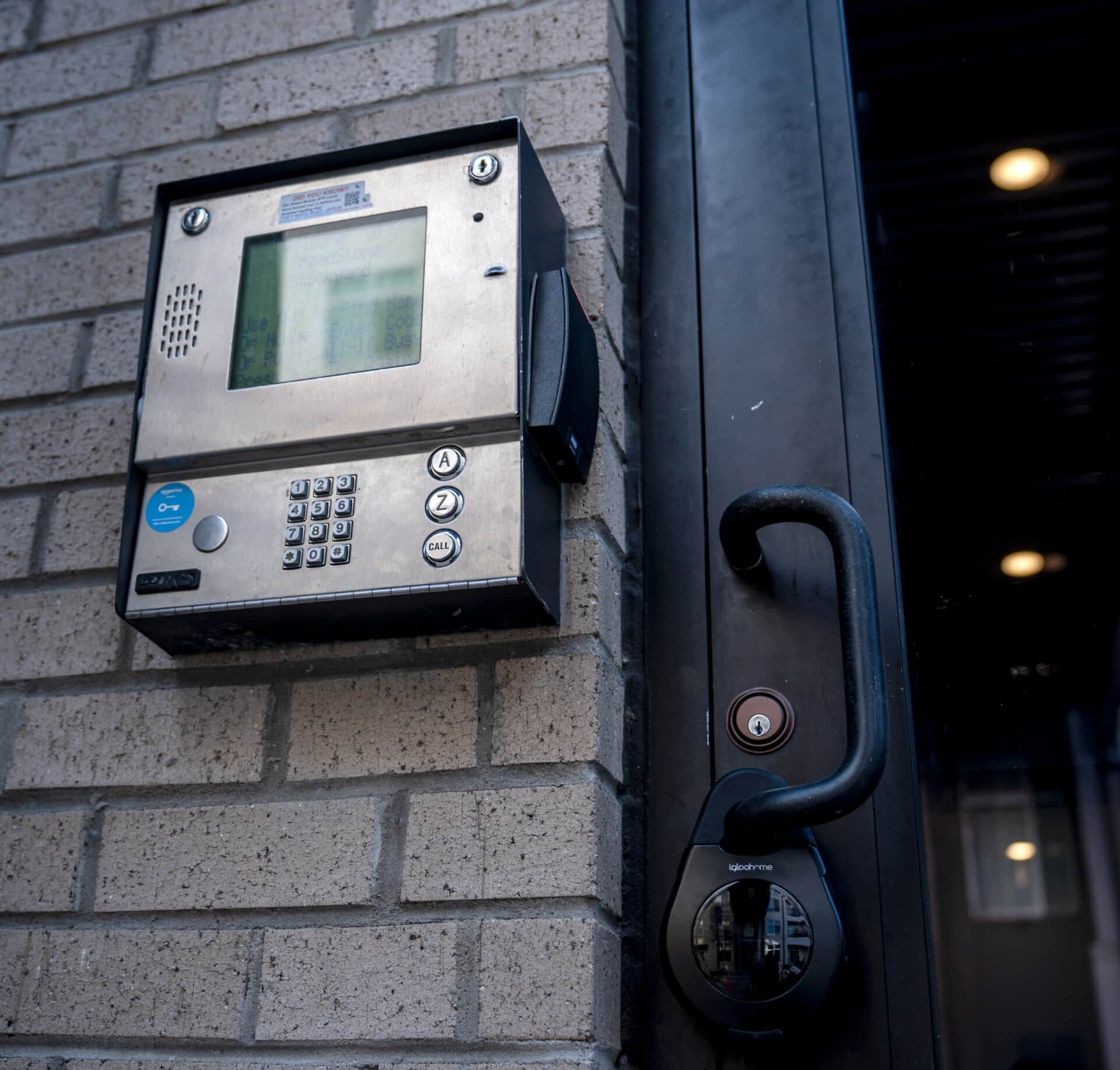 A keypad on a brick wall next to a door