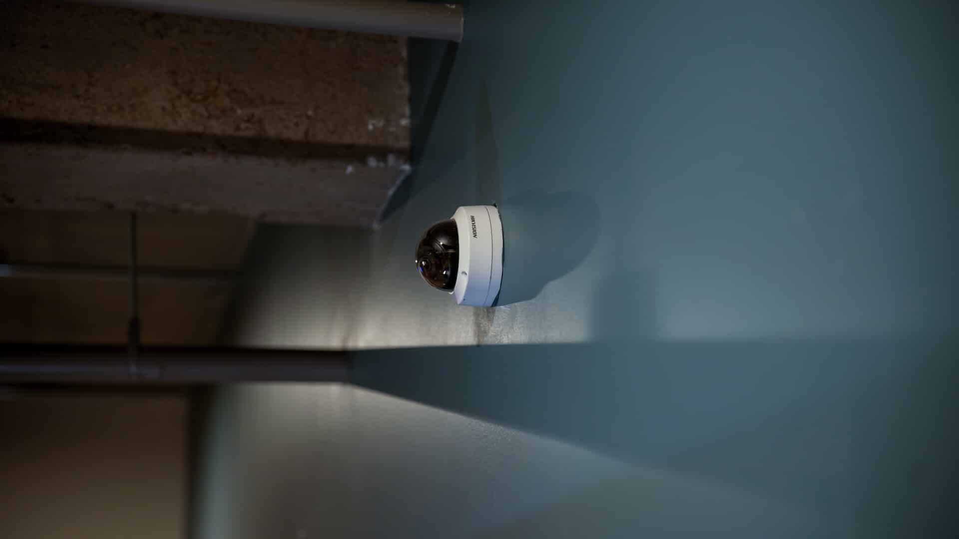 A security camera is hanging from the ceiling of a building.