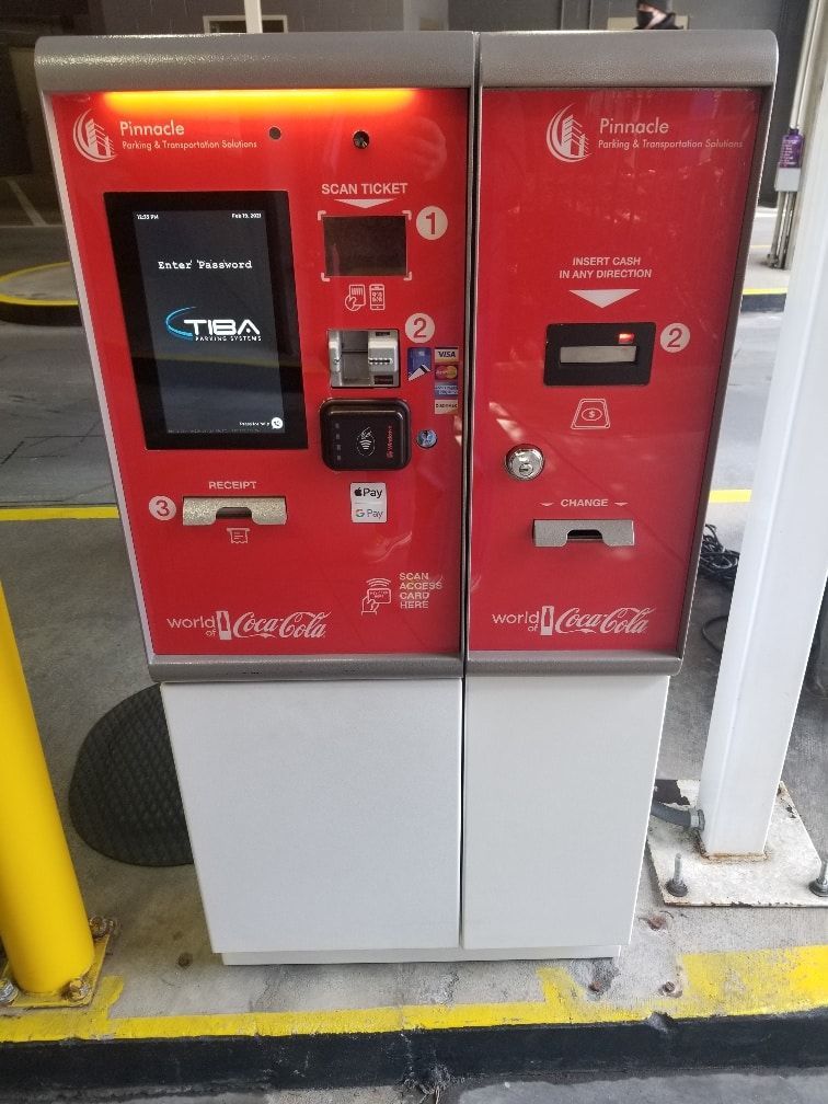 A coca cola vending machine is sitting in a parking lot