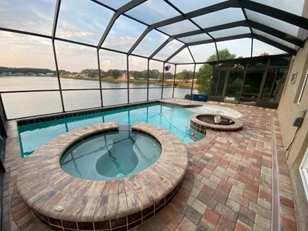 Screened pool deck with hot tub and canal view at sunset