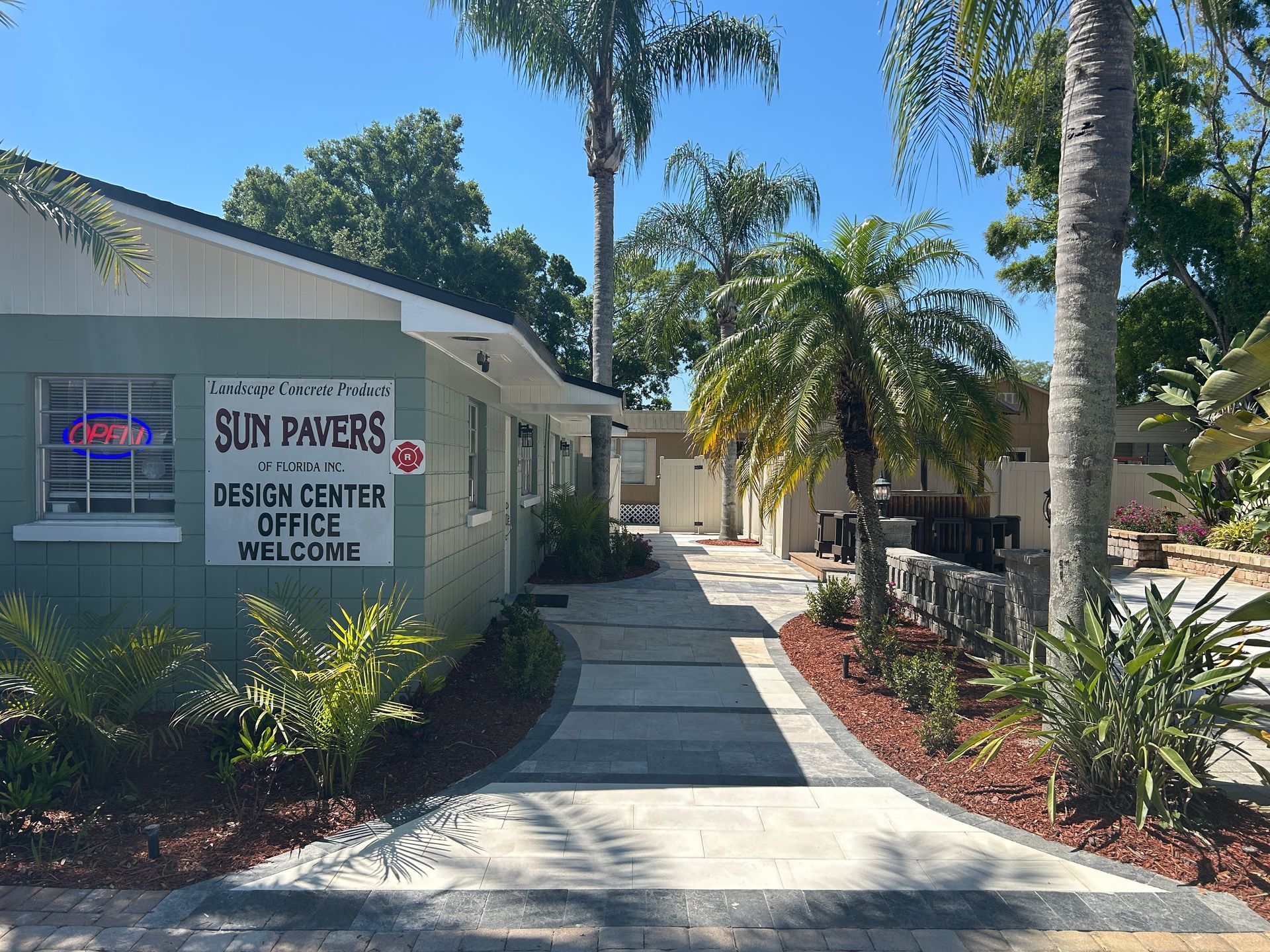 Clinic entrance with walkway, palm trees, and sign for Sun Pavers and eye center offices