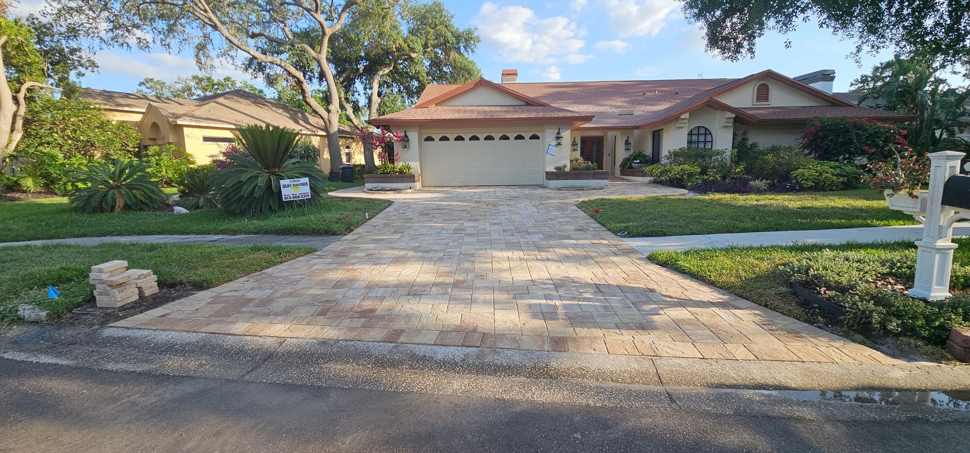 Suburban house with a two-car garage, long driveway, and landscaped front yard at dusk