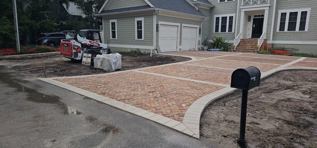 House front with a fresh gravel driveway, curved concrete border, and mailbox by the curb.