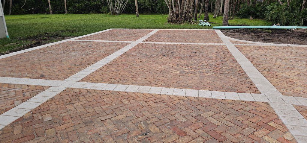 Brick and gravel courtyard with white painted grid lines, bordered by grass and trees