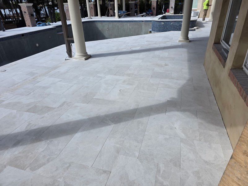 Empty tiled walkway with columns and a shadow across the floor outdoors
