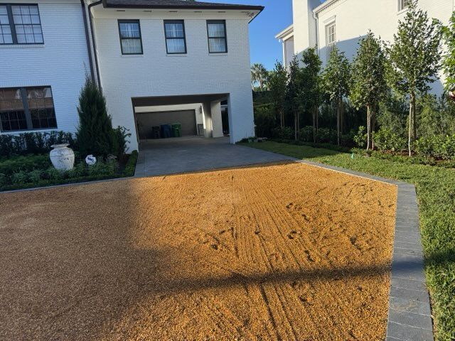 Newly leveled brown gravel driveway leading to a modern house with a garage.