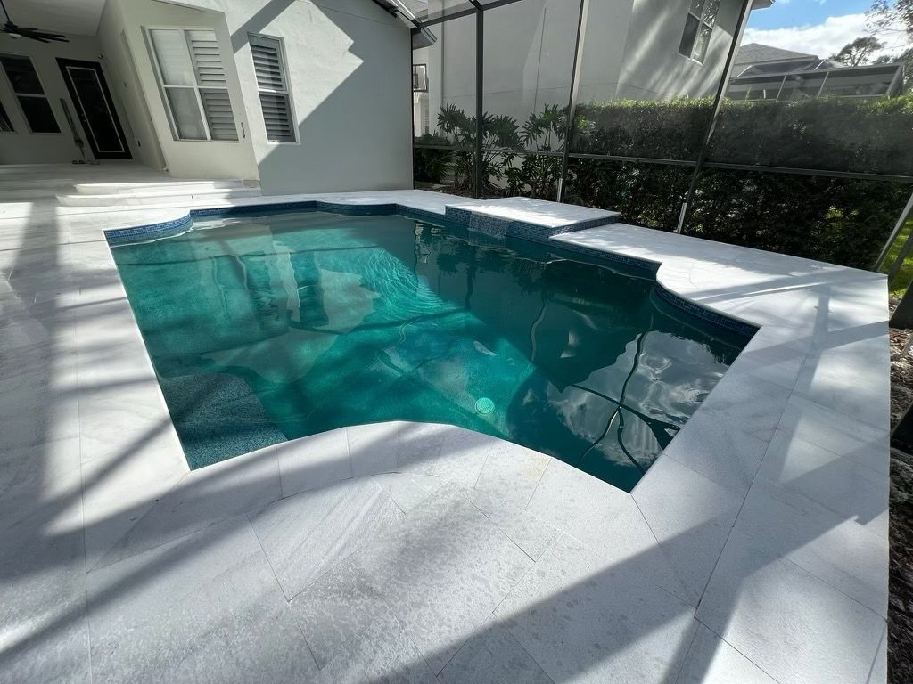 Modern backyard with a turquoise swimming pool, white deck, and house exterior in bright sunlight