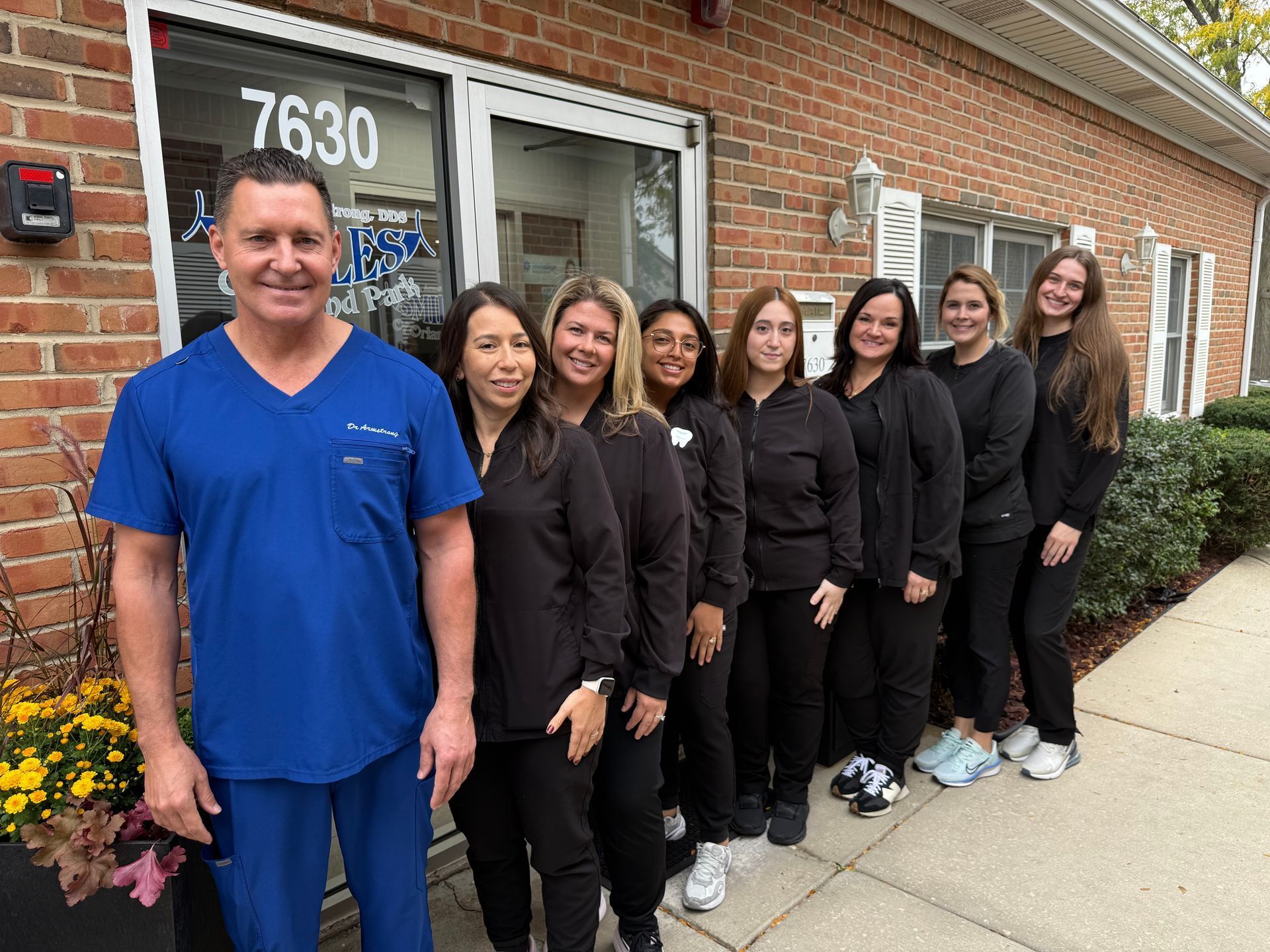 Group of medical staff in front of a brick building entrance.  The staff wear scrubs.