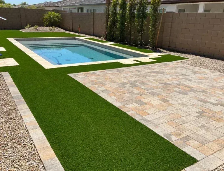 Backyard patio with a rectangular pool, green turf strips, and beige paver seating area